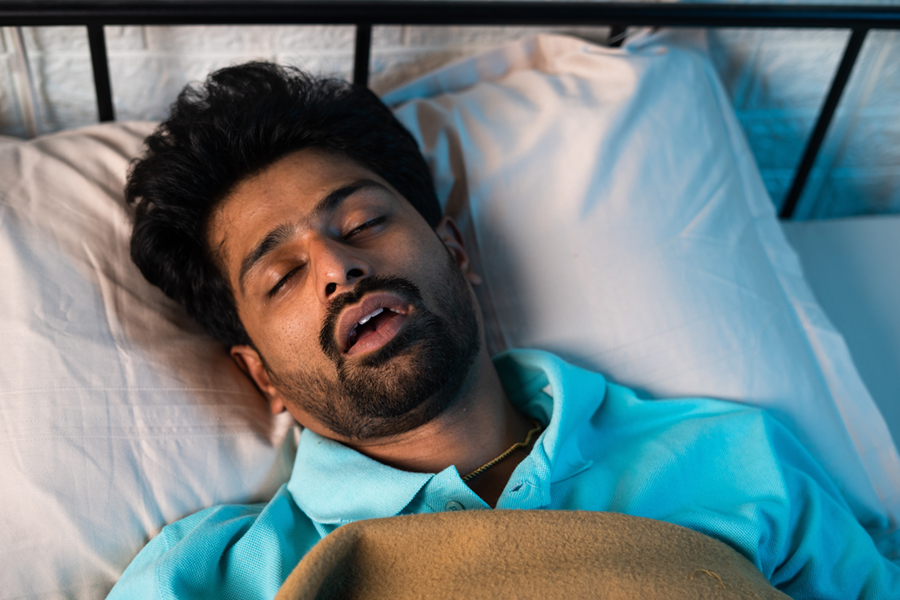 close up shot of man sleeping by snoring with mouth open during night - concept of relaxation, apnea and napping